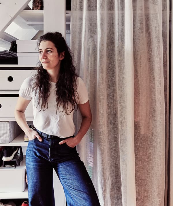 Woman standing in front of clothes storage behind a curtain.