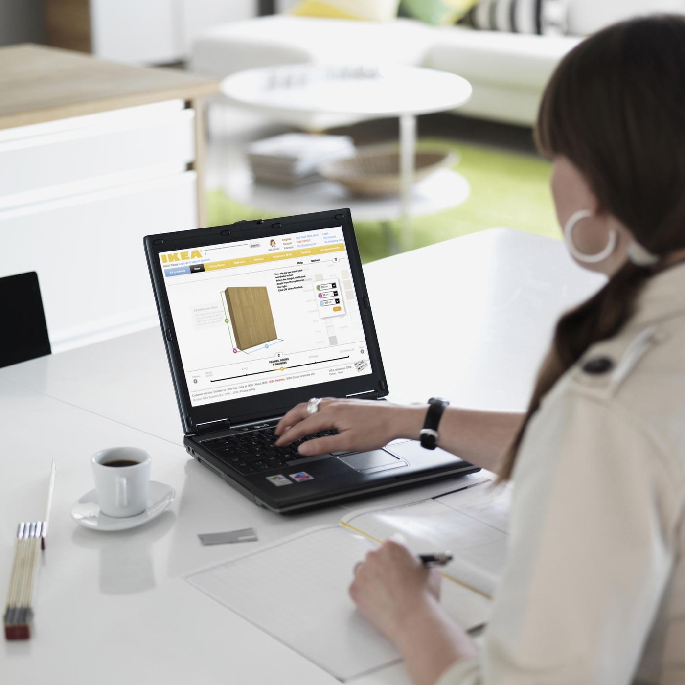 Woman working on laptop on white desk, using online planning tool