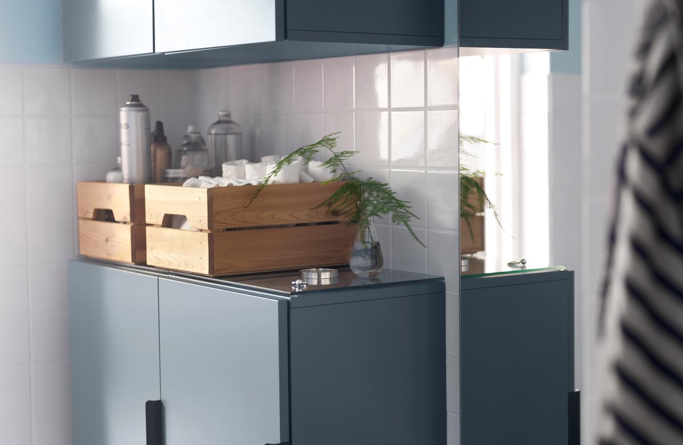 Wooden boxes on top of blue cabinets help organise bathroom essentials.