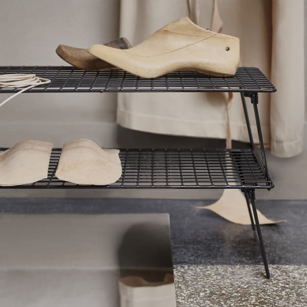 Wooden shoe trees on stacked black shoe racks.