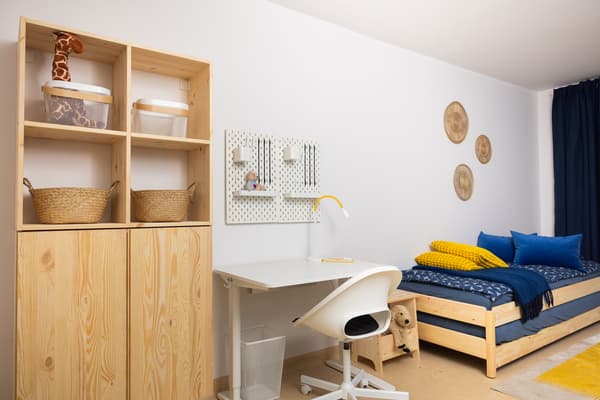 Work and storage area in a family room with IKEA desk, shelving, and wooden furniture.