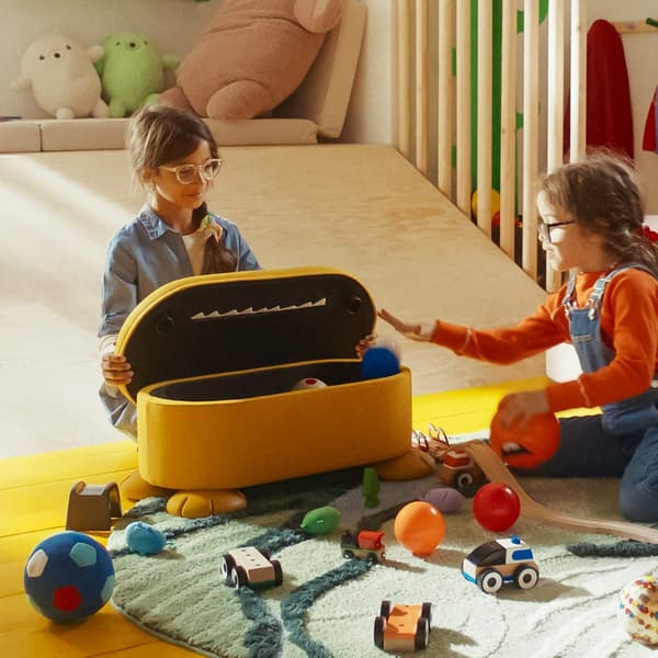 Yellow GREJSIMOJS pouffe with built-in storage and playful teeth design, used for seating and tidying toys.