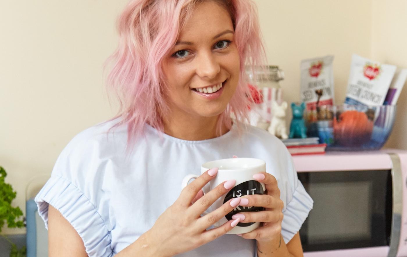 Young woman with pink hair smiling into the camera.