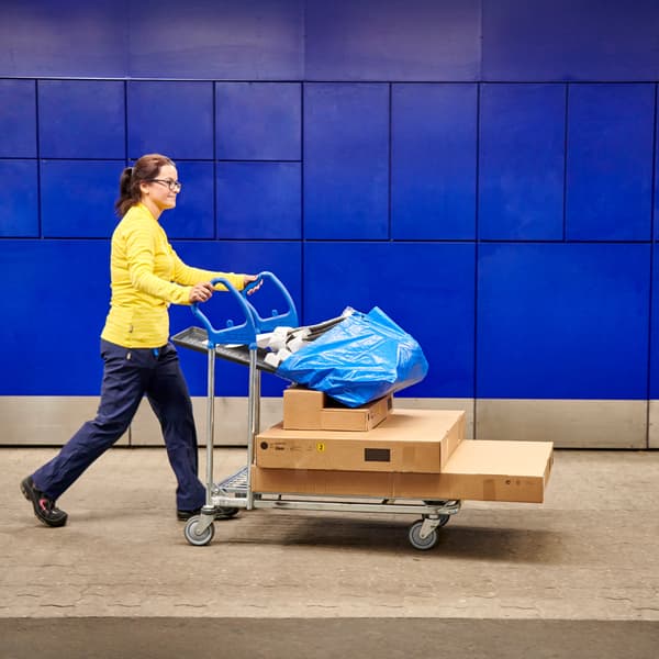 Zaměstnanec IKEA tlačí naložený vozík.