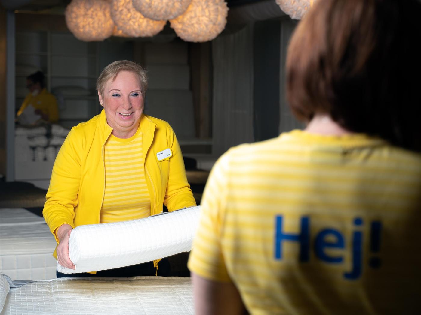 Zaměstnankyně IKEA dává polštář na postel.