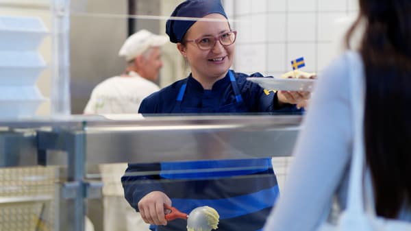 Zaměstnankyně IKEA vydává jídlo na talíři.
