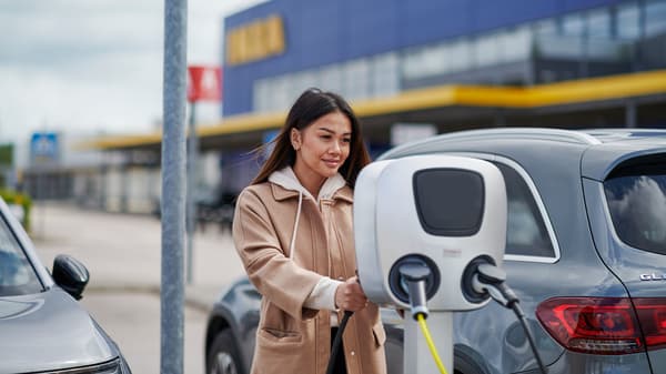Žena před obchodním domem IKEA, která využívá nabíjecí elektrostanici.