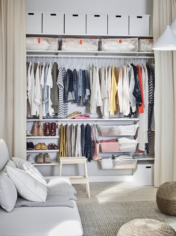 Zimmer, in dem eine Wand mit bodenlangen Gardinen versehen ist und den Blick auf eine breite BOAXEL Kleiderschranklösung eröffnet.