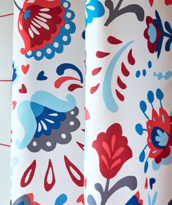 Zoomed-in section of a shower curtain, brightly coloured and decorated with a traditional Swedish kurbits pattern.