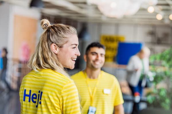 Zwei IKEA Mitarbeitende in gelber Uniform lachen.
