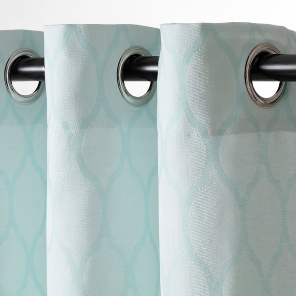 Two turquoise curtains with medallion patterns hang on silver grommets, providing privacy and light control.