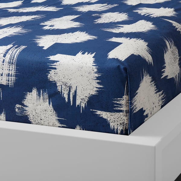 Blue bedspread with white brush strokes pattern, folded on white surface, showcasing soft cotton fabric.