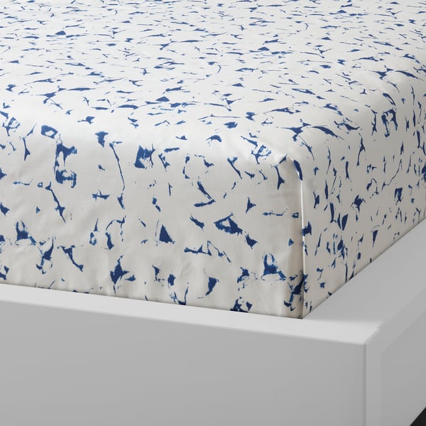 Blue and white patterned fitted sheet on white bed, high quality cotton, soft feel.