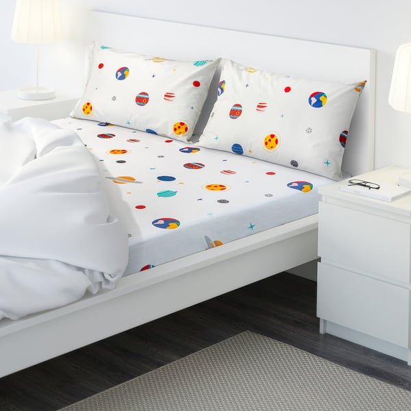 Bed with colourful planet bedding, two nightstands, and lamps in a cosy room.