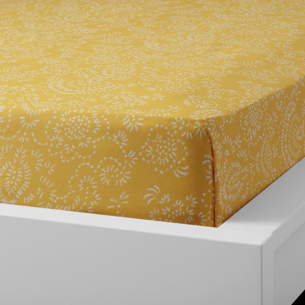 Yellow patterned cotton flat sheet displayed on a white bed, showcasing its soft, breathable fabric and envelope pillowcase design.