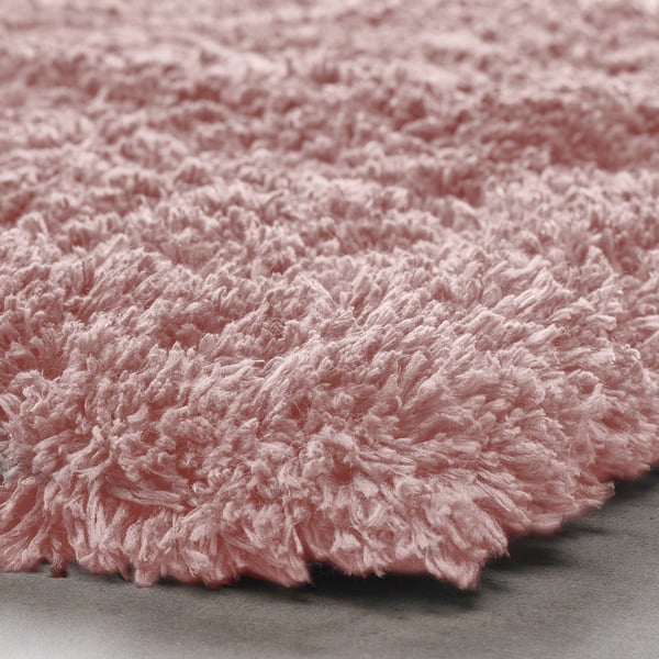 Soft pink shaggy rug close-up, showing thick, fluffy texture.