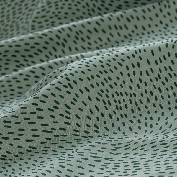 Soft, green polka dot bedsheet, smooth cotton-lyocell blend, neatly folded, showcasing elegant texture.