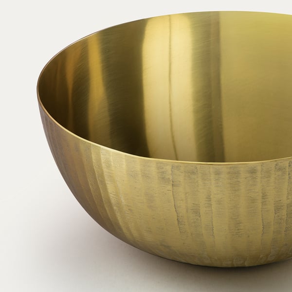 Golden bowl with etched exterior, smooth interior, elegant and festive, resting on a surface.