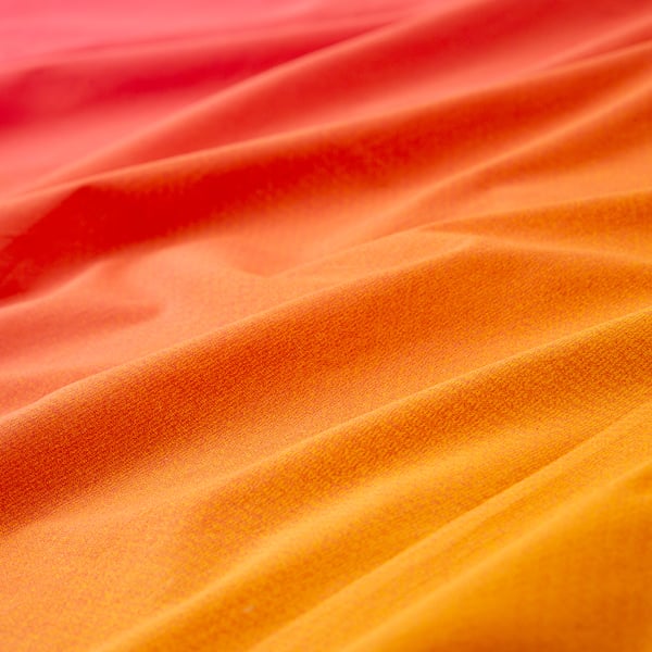 Smooth, luxurious fabric in shades of red and orange; soft, high-quality texture.