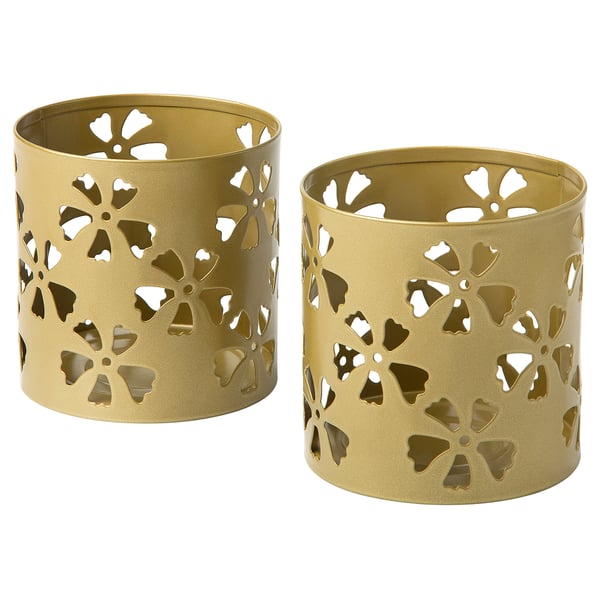 Two gold-colored cylindrical candle holders with intricate floral cutouts, made from coated galvanised steel, creating a warm and festive atmosphere.
