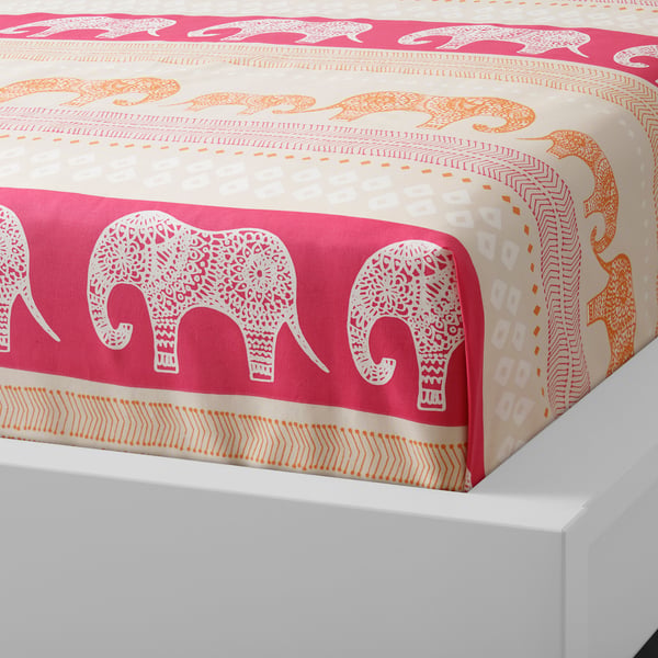 Bright bedspread with white and orange elephants on red and beige patterns on a mattress.