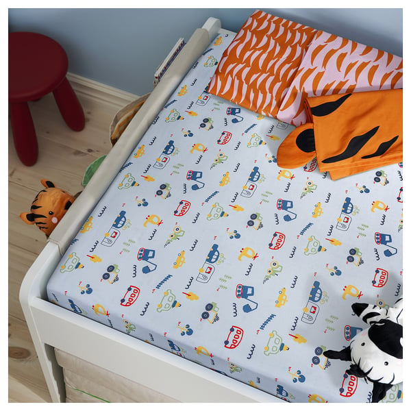 Childs bed with colourful vehicle print bedding. Orange and white stuffed animals. Blue walls and wooden floor.