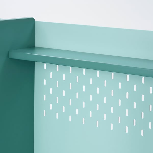 Close-up of a green storage solution with holes for hooks, part of a childrens desk with adjustable height.