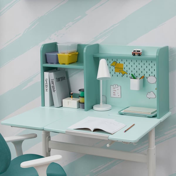 Desk with adjustable height and tilted work surface, storage shelf, and pegboard.