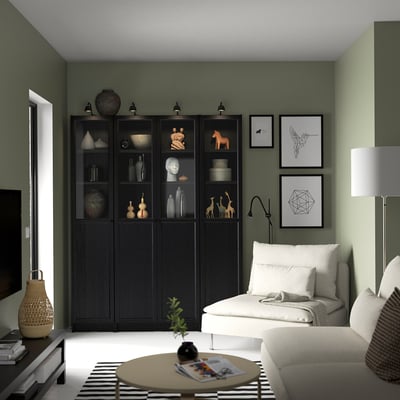 Modern living room with BILLY bookcase, green walls, white couch, lamp & art prints.
