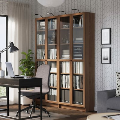 BILLY bookcase in modern home office with glass doors, books, plants, and pictures.