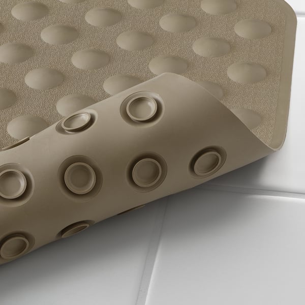 Close-up of a beige bath mat with suction cups, highlighting its strong grip and draining hole for drying.