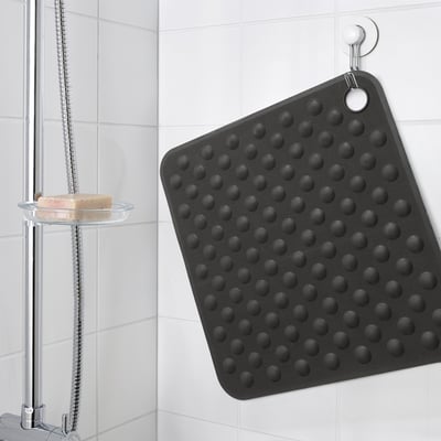 Black bath mat with suction cups hangs on wall.