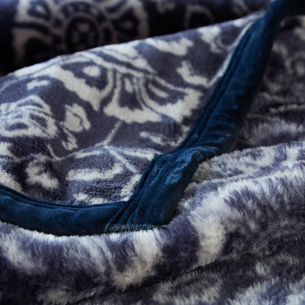 Thick, patterned fleece blanket with stitched seams, showcasing intricate floral design, displaying soft and warm fabric quality.