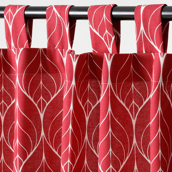 Red patterned curtains hang closed, featuring white abstract designs. Showing eyelet tabs for rod, offering privacy and light control.