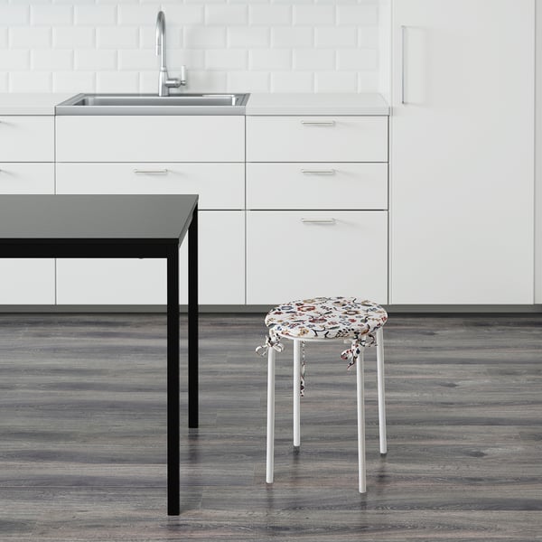 Decorative kitchen stool with floral seat by sink.