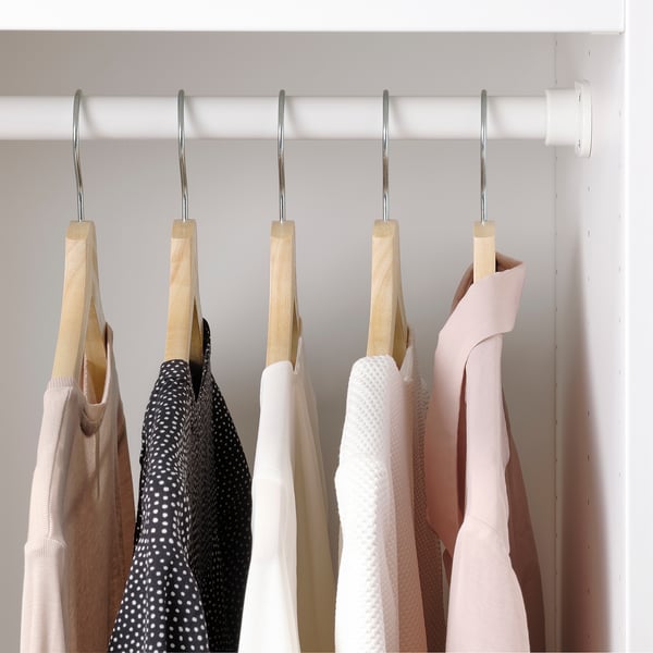 Clothes hangers with wooden bars keep garments neat and organised in a wardrobe.