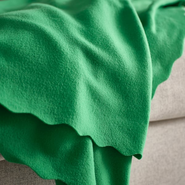 Green fleece blanket draped on a couch. Soft texture visible.
