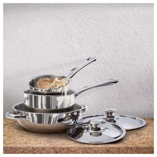 Stainless steel cookware set: saucepot, skillet, wok, and lids. Modern, metallic, with comfortable handles and flat bases.