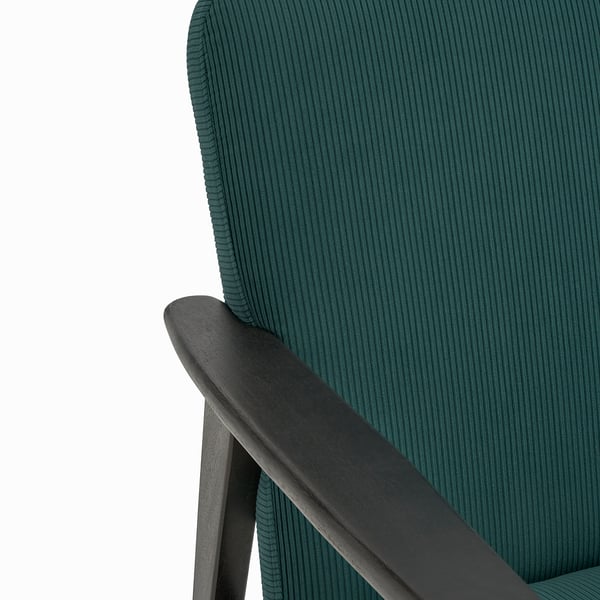 Dark green textured sofa with sleek wooden arm, showcasing high-quality craftsmanship.