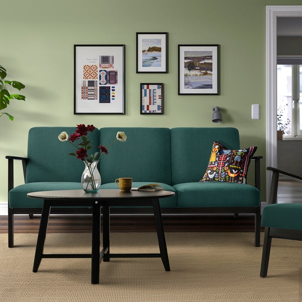 Green EKENÄSET sofa, art, coffee table, flowers, pillow, matching armchair.