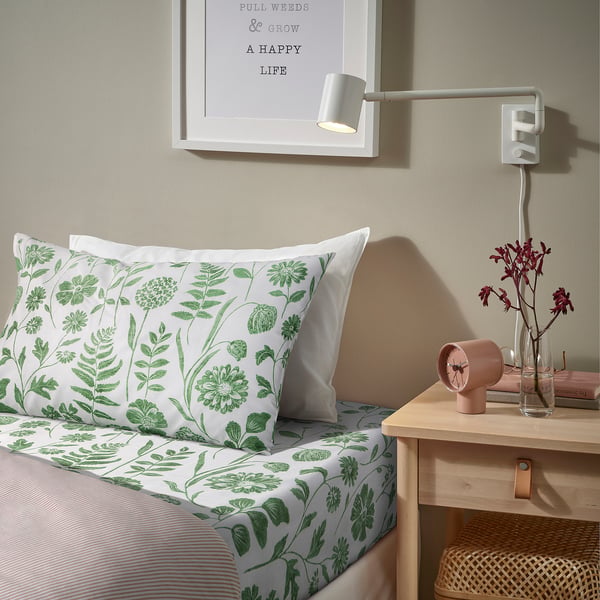 Green bedding, striped blanket, pink clock, flowers, cosy light