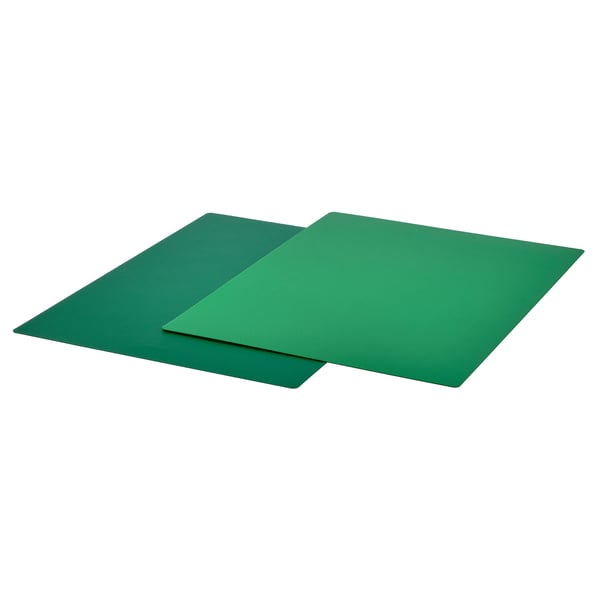 Two green flexible chopping boards, one over the other, with anti-slip undersides, made of thermoplastic elastomer.