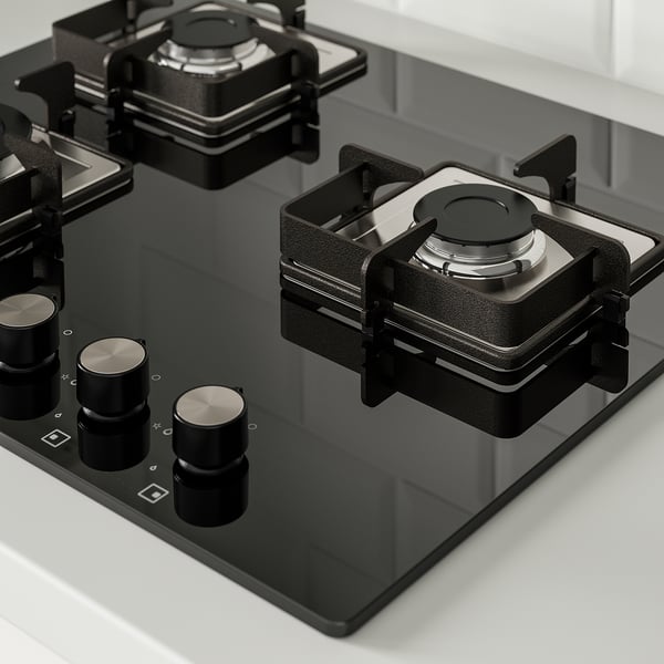 Modern gas cooktop with black glass surface, featuring cast iron supports and metallic knobs for precise heat control.
