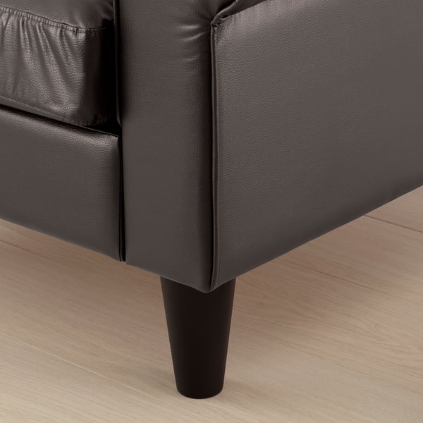 Close-up of black GAMMALBYN sofa leg, showcasing sleek design and sturdy build on wooden floor.