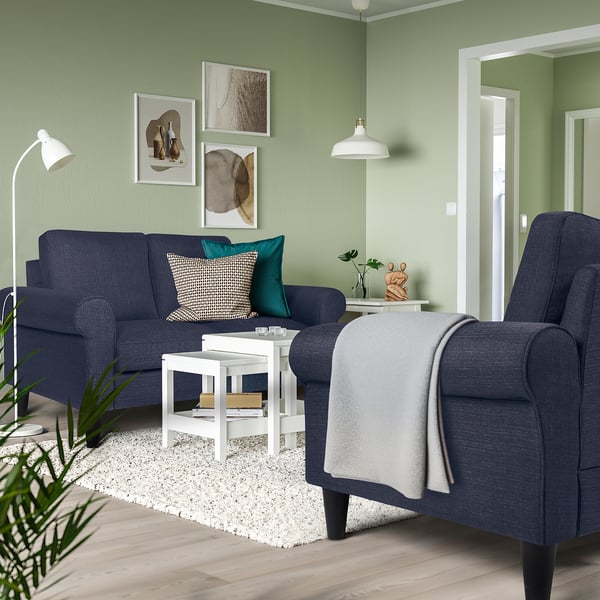 Modern living room: dark blue GAMMALBYN sofa & chair, soft art wall, white rug, cosy decor.