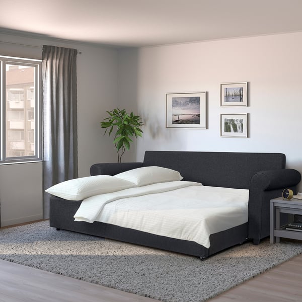 Modern grey sofa-bed with white bedding, smooth lines, small prints on rug, fits cosily under large wall art, perfect for compact spaces.