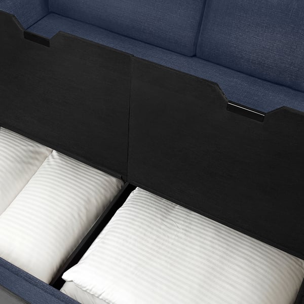 A modern sofa-bed with blue and dark fabric, showcasing its transforming design with included pillows.