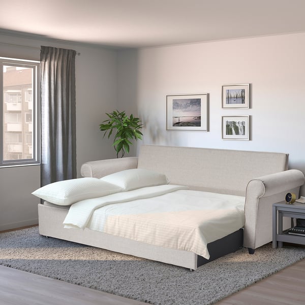 Beige GAMMALBYN sofa-bed with white bedding, compact & modern.