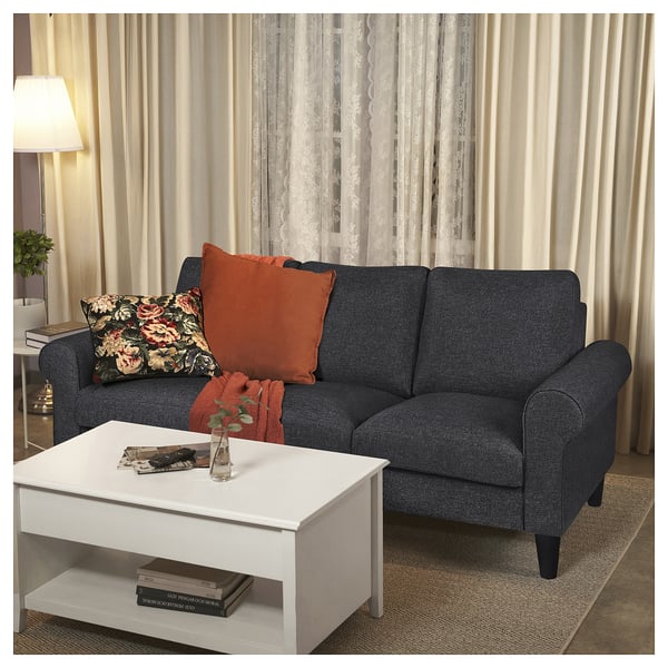 Modern living room with GAMMALBYN dark grey sofa, white coffee table, colourful pillows, and large curtains.