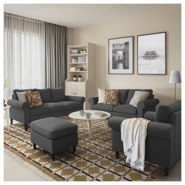 Modern living room with GAMMALBYN grey sofa set, white coffee table, patterned rug, two framed photos, and a bookshelf.